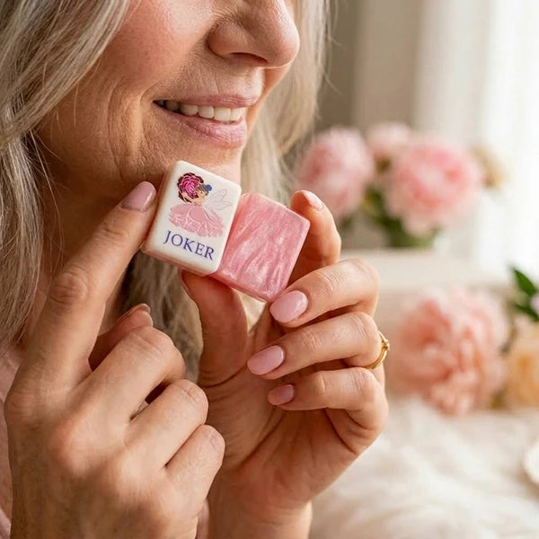 Hand holding a rose-pink mother-of-pearl Mahjong tile